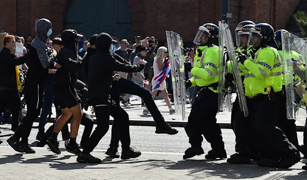 Police officers face protesters outside in Liverpool on August 3, 2024. (AFP)