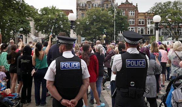 Police officers watch members of the public outside the Town Hall during a vigil to remember the victims of the stabbing attack last Monday in Southport, England, Monday, Aug. 5, 2024. (AP)