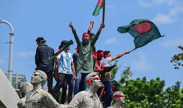 Demonstrators perched on a monument in memory of victims of terrorism waving Bangladeshi flags in Dhaka, August 4, 2024. (AFP)