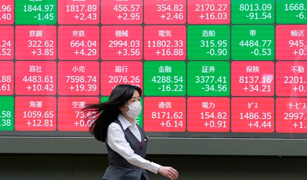 People walk past an electronic stock board showing the sectors' index of Japanese stocks outside a securities firm in Tokyo, on June 7, 2024. (AP)