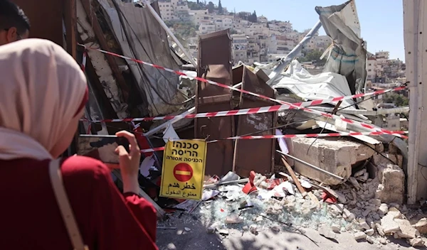 Palestinians stand by the rubble of the demolished shop, June 29, 2021. (AFP)