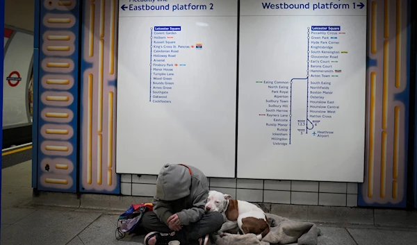 A homeless person sits with their dog in an underground station in London, Saturday, Nov. 18, 2023. (AP)