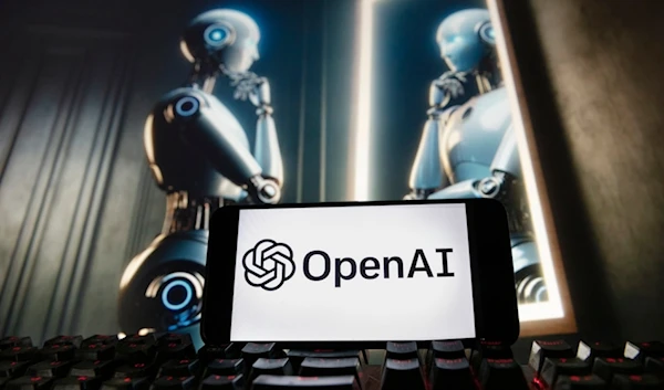 The OpenAI logo is displayed on a cell phone with an image on a computer monitor generated by ChatGPT's Dall-E text-to-image model, Dec. 8, 2023, in Boston. (AP)