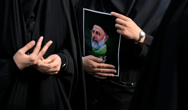 An Iranian woman holds a poster of the late President Ebrahim Raisi during a mourning ceremony for him at Vali-e-Asr square in downtown Tehran, Iran on May 20, 2024 (AP)