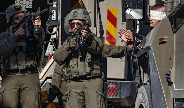 IOF soldiers point their guns as they arrest a blindfolded Palestinian during an ongoing military operation in Tubas in the north of the occupied West Bank on September 11, 2024. (AFP)