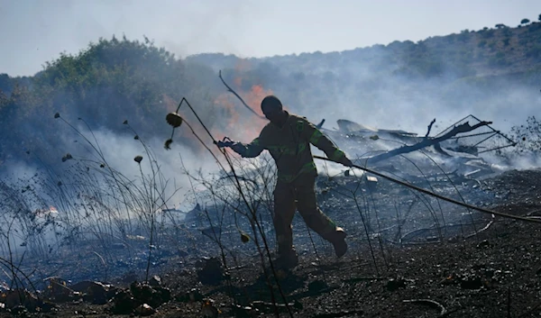 An Israeli firefighter works to extinguish a fire burning in an area near the community of Ramot Naftali, by the border with Lebanon, northern occupied Palestine, Tuesday, June 4, 2024. (AP)