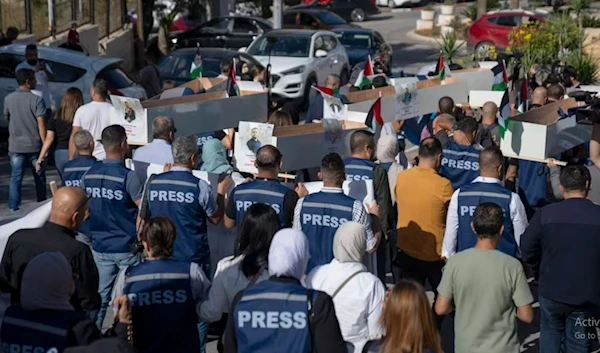 Palestinian journalists carried mock coffins in a symbolic funeral procession toward a United Nations office in the West Bank city of Ramallah on November 7, 2023. (AP)