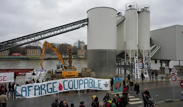 Activists of the environmental group Extinction Rebellion hold a banner reading "Lafarge guilty" outside the Cemex cement plant sits in Paris, Sunday, Dec. 10, 2023. (AP)