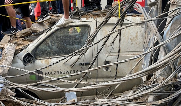 People stand on top of a damaged car at the scene of a missile strike in the southern suburbs of Beirut, Friday, Sept. 20, 2024. (AP Photo/Bilal Hussein)