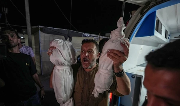 Osama al-Taweel holds up the bodies of his grandchildren who were killed in an Israel airstrike on the Gaza Strip, as he arrives at the hospital morgue in Deir al-Balah, in Palestine, on August 29, 2024. (AP)