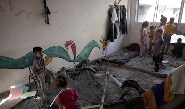 Palestinian children navigate heavy damage to a UNRWA school sheltering forcibly displaced Palestinians in Khan Younis, southern Gaza Strip, on Friday June 21, 2024. (AP)