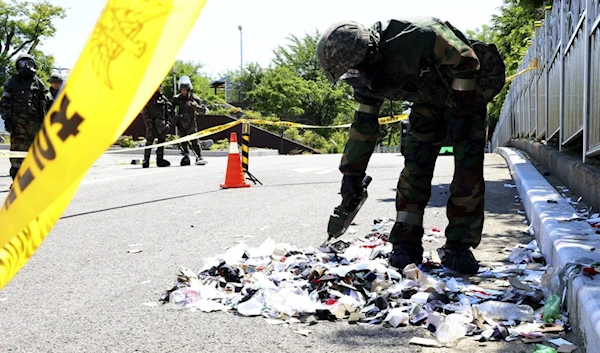 South Korean soldier wearing protective gears checks the trash from a balloon presumably sent by North Korea, in Incheon, South Korea, on June 2, 2024. (AP)