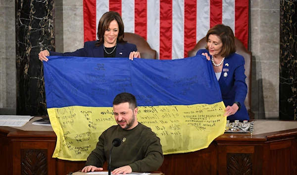 President Volodymyr Zelensky addresses Congress as Rep. Nancy Pelosi and Vice President Kamala Harris hold up a Ukrainian national flag signed by Ukrainian soldiers at the Capitol in Washington on Wednesday, December 21. (AFP/Getty Images)