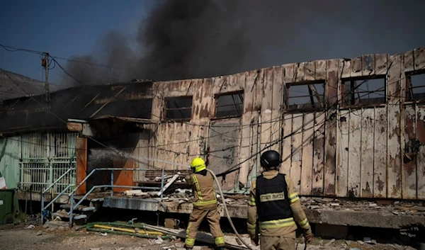 Firefighters work to extinguish a fire after a rocket, fired from Lebanon, hit a local municipality storage in Kiryat Shmona, northern occupied Palestine, September 24, 2024 (AP)