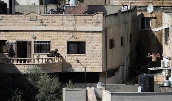 A man holds his hand while in the sight of two Israeli soldiers in the West Bank town of Qabatiya during a raid, Thursday, September 19, 2024 (AP)