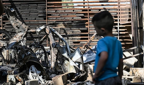 A Palestinian child stares at a car, destroyed by Israeli occupation forces, inside the garage of a home in Jenin in the occupied West Bank, occupied Palestine, on August 31, 2024. (AFP)