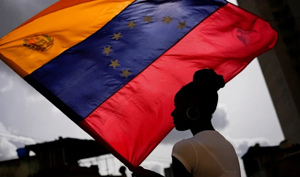 A woman holds a Venezuelan flag during the Saint John the Baptist feast in the San Agustin neighborhood of Caracas, Venezuela, Friday, June 24, 2022. (AP Photo/Matias Delacroix)