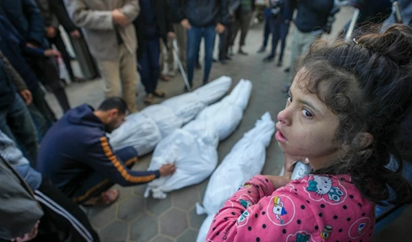 A girl watches as Mohammad Eid mourns his cousin Dima, along with her uncle and grandfather, who were killed in an Israeli airstrike on Saturday, during their funeral in Deir al-Balah, central Gaza Strip, Sunday, Jan. 12, 2025. (AP)