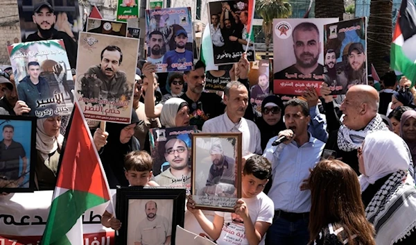 Palestinians hold photographs of detainees held by the Israeli occupation during a rally marking the annual prisoners’ day in the West Bank city of Nablus, on April 17, 2024. (AP)