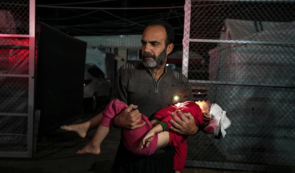 A Palestinian man carries a wounded girl, following an Israeli bombardment on the Gaza Strip, as they arrive at the Al-Aqsa Martyrs hospital in Deir al-Balah, on Janaury 14, 2025. (AP)