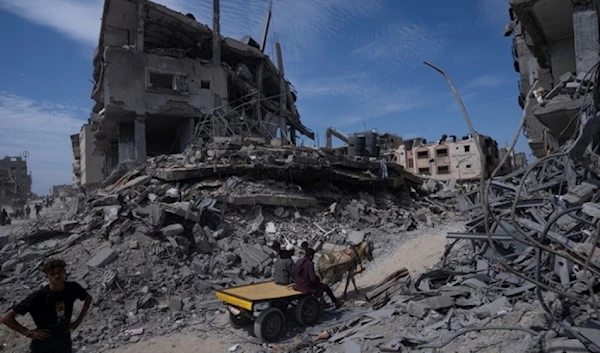 Palestinians walk through the destruction in the wake of the Israeli air and ground attack in Khan Younis, southern Gaza Strip, Palestine, April 8, 2024. (AP)