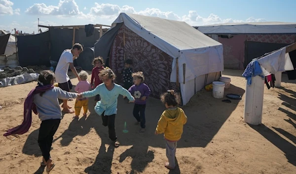 Children play next to their tent in a refugee camp in Deir al-Balah, Gaza Strip, on November 19, 2024 (AP)