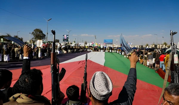 People gather around a giant Palestinian flag during an anti-Israeli rally in Sanaa, Yemen, Friday, Jan. 10, 2025 (AP)