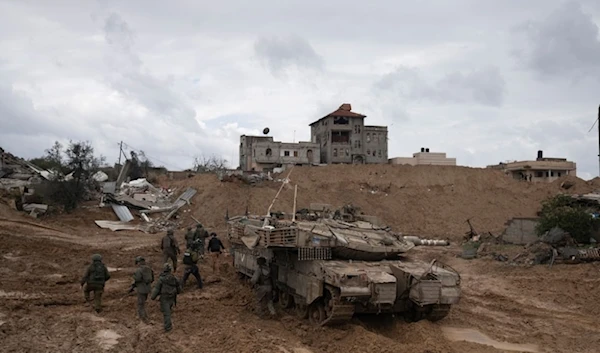 IOF soldiers walk by a tank during the ground invasion of the Gaza Strip in Khan Younis on Saturday Jauary 27,2024. (AP)