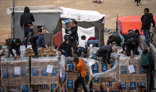 Palestinians grab humanitarian aid from a truck as it crossed into the Gaza Strip in Rafah, Dec. 17, 2023 (AP)