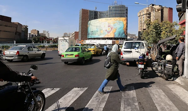 People walk and drive past a billboard covering the facade of a building on Vali-Asr square in Tehran, Iran, October 26, 2024. (AFP)