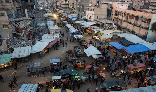 Palestinians walk along a street market in Khan Younis, central Gaza Strip, Saturday, Jan. 18, 2025 (AP)