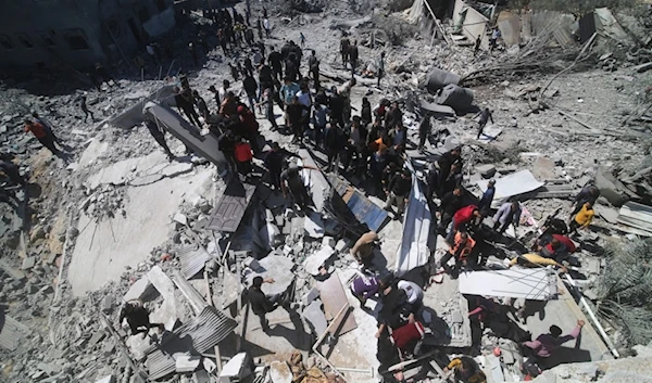 Palestinians look at residential building, destroyed by an Israeli strike in Rafah on March 20, 2024. (AP)