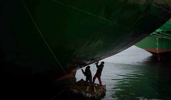 Men work on a cargo ship docked at a terminal of the port of Latakia, Syria, Monday, Dec. 16, 2024. (AP Photo/Leo Correa)