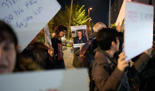 A woman holds a sign featuring a photo of Palestinian Dr. Hussam Abu Safiya during a protest in front of the Shin Bet offices, calling for his release, in 'Tel Aviv', occupied Palestine on January 1, 2025. (AP)